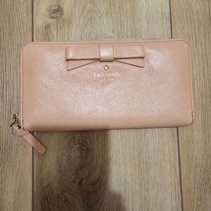 Kate Spade pink pebbled leather zip-around wallet with a signature bow detail.